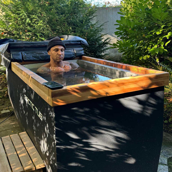 Daniel Aminati sitzt in einem Mammut-Eisbad-Behälter im Freien, umgeben von Grün. Ideal für Eisbäder, Kältetherapie und Outdoor-Kälteanwendungen.